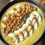 Die Hauptzutaten sind einfach und lecker. Du brauchst: - 2 reife Bananen, gefroren - 1 Tasse ungesüßte Mandelmilch (oder Milch deiner Wahl) - 3 Esslöffel Erdnussbutter - 1 Esslöffel Honig oder Ahornsirup (optional) - 1/2 Teelöffel Vanilleextrakt - 1/4 Teelöffel Zimt Diese Zutaten machen die Basis für die cremige und nahrhafte Smoothie-Bowl. Die gefrorenen Bananen geben eine kühle und dicke Konsistenz. Erdnussbutter sorgt für einen nussigen Geschmack und gesunde Fette. Toppings bringen den besonderen Genuss. Hier sind meine Favoriten: - 1/4 Tasse Granola - Frisch geschnittene Bananenscheiben - Gehackte Erdnüsse - Eine Prise Chiasamen - Ein Spritzer zusätzliche Erdnussbutter Diese Toppings fügen Textur und zusätzlichen Geschmack hinzu. Granola bringt Knusprigkeit, während frische Bananen einen süßen Biss bieten. Chiasamen sind ein toller Nährstoffbooster. Wenn du etwas anderes probieren willst, sind hier einige Ersatzstoffe: - Verwende Kokosmilch anstelle von Mandelmilch für einen tropischen Geschmack. - Ersetze Erdnussbutter durch Mandel- oder Cashewbutter für Abwechslung. - Statt Honig kannst du Agavendicksaft verwenden, wenn du vegan bleiben möchtest. Diese Alternativen halten die Smoothie-Bowl spannend und lecker. Experimentiere mit dem, was dir schmeckt! Um die Smoothie-Bowl zu machen, beginne mit den Zutaten. Du brauchst: - 2 reife Bananen, gefroren - 1 Tasse ungesüßte Mandelmilch - 3 Esslöffel Erdnussbutter - 1 Esslöffel Honig oder Ahornsirup (optional) - 1/2 Teelöffel Vanilleextrakt - 1/4 Teelöffel Zimt - Toppings: - 1/4 Tasse Granola - Frisch geschnittene Bananenscheiben - Gehackte Erdnüsse - Eine Prise Chiasamen - Ein Spritzer zusätzliche Erdnussbutter Schneide die gefrorenen Bananen in Stücke. Dies macht das Mixen leichter. Stelle sicher, dass alle Zutaten bereit sind, bevor du anfängst. Gib die geschnittenen Bananen in den Mixer. Gieße die Mandelmilch darüber. Füge dann die Erdnussbutter, den Honig, den Vanilleextrakt und den Zimt hinzu. Mixe alles auf hoher Geschwindigkeit. Stoppe zwischendurch, um die Seiten des Mixers abzuschaben. Mixe, bis die Mischung glatt und cremig ist. Probiere die Mischung und passe die Süße nach deinem Geschmack an. Wenn du mehr Honig oder Ahornsirup magst, gib es jetzt dazu und mixe kurz weiter. Gieße die fertige Smoothie-Mischung in eine Schüssel. Jetzt kommt der spaßige Teil: das Anrichten! Garniere die Oberfläche mit frischen Bananenscheiben, Granola, gehackten Erdnüssen und einer Prise Chiasamen. Diese Toppings geben der Bowl Textur und Knusprigkeit. Träufle zum Schluss etwas Erdnussbutter über die Toppings. So erhält die Bowl einen extra nussigen Geschmack. Jetzt ist deine Erdnussbutter-Bananen-Smoothie-Bowl fertig und sieht toll aus! Um deine Smoothie-Bowl noch cremiger zu machen, kannst du die gefrorenen Bananen länger einfrieren. Eine gute Mischung ist wichtig. Achte darauf, dass du die Zutaten gut pürierst. Das macht die Textur wunderbar glatt. Füge auch etwas mehr Mandelmilch hinzu, wenn es zu dick ist. Diese Smoothie-Bowl ist perfekt für Meal Prep. Du kannst die Zutaten im Voraus vorbereiten. Schneide die Bananen und friere sie ein. Mische die trockenen Zutaten wie Granola und Nüsse in einem Behälter. So hast du alles bereit, wenn du es brauchst. Einfach die gefrorenen Bananen mit der Milch und Erdnussbutter mixen, und schon hast du ein schnelles Frühstück. Um mehr Geschmack hinzuzufügen, probiere andere Toppings. Frische Beeren, Kokosraspeln oder sogar Schokoladenstückchen sind lecker. Für zusätzlich Nährstoffe sind Chiasamen oder Leinsamen toll. Diese kleinen Samen bringen Omega-3-Fettsäuren mit. Du kannst auch einen Löffel Proteinpulver dazugeben, um es sättigender zu machen. {{image_4}} Für eine schokoladige Note kannst du Kakaopulver hinzufügen. Verwende zwei Esslöffel ungesüßtes Kakaopulver. Das kombiniert perfekt mit der Erdnussbutter. Es ergibt eine leckere, süße Mischung. Du kannst auch Schokoladenstückchen als Topping nutzen. Das macht die Bowl noch verlockender. Wenn du vegan leben möchtest, ist das einfach! Ersetze die Milch durch pflanzliche Alternativen. Mandelmilch funktioniert gut, aber auch Hafer- oder Sojamilch sind toll. Verwende Ahornsirup anstelle von Honig. So bleibt die Bowl zu 100 Prozent pflanzlich. Du kannst auch andere Früchte hinzufügen. Erdbeeren, Himbeeren oder sogar Mangos passen gut. Sie bringen frische Aromen in die Bowl. Wenn du mehr Geschmack möchtest, probiere einen Hauch von Kokosnuss. Geraspelte Kokosnuss als Topping macht alles noch besser. Experimentiere mit verschiedenen Kombinationen! Die Erdnussbutter-Bananen-Smoothie-Bowl bleibt frisch, wenn du sie richtig lagerst. In einem verschlossenen Behälter hält sie sich bis zu zwei Tage im Kühlschrank. Der Geschmack bleibt gut, aber die Textur kann sich leicht verändern. Achte darauf, dass sie nicht länger als zwei Tage bleibt, da die Bananen braun werden können. Um Reste richtig zu lagern, benutze einen luftdichten Behälter. Fülle die Smoothie-Bowl nicht zu voll, damit sie atmen kann. Decke die Bowl mit Frischhaltefolie ab, um Oxidation zu vermeiden. Wenn du die Bowl länger aufbewahren willst, lagere die Toppings separat. So bleibt alles frisch und knusprig. Du kannst die Zutaten auch einfrieren. Teile die gefrorenen Bananen in Portionen auf und lege sie in einen Gefrierbeutel. So sind sie immer bereit für deine nächste Smoothie-Bowl. Wenn du die ganze Bowl einfrieren willst, tue dies in einem gefrierfesten Behälter. Achte darauf, die Bowl vor dem Essen langsam im Kühlschrank aufzutauen. So bleibt der Geschmack optimal erhalten. Eine Erdnussbutter-Bananen-Smoothie-Bowl hat etwa 350 bis 450 Kalorien, je nach Zutaten. Die gefrorenen Bananen liefern natürliche Süße und Ballaststoffe. Erdnussbutter fügt gesunde Fette und Proteine hinzu. Granola als Topping kann die Kalorienzahl erhöhen. Schauen Sie auf die Portionsgröße, um die Kalorien zu steuern. Ja, du kannst Erdnussbutter ersetzen. Mandelbutter ist eine gute Option. Cashewbutter hat einen milden Geschmack. Sonnenblumenbutter ist eine tolle Wahl für Allergiker. Alle diese Optionen bieten eine ähnliche Cremigkeit und Textur. Achte darauf, die Konsistenz und den Geschmack der Smoothie-Bowl zu testen. Ja, die Smoothie-Bowl ist perfekt für Kinder! Sie ist nahrhaft und lecker. Kinder lieben die Süße der Bananen und die Cremigkeit der Erdnussbutter. Du kannst die Süße mit Honig anpassen. Mit bunten Toppings wird die Bowl noch ansprechender. Es ist eine großartige Möglichkeit, gesunde Zutaten in die Ernährung der Kinder einzuführen. Die Erdnussbutter-Bananen-Smoothie-Bowl ist einfach und lecker. Wir haben die besten Zutaten, Toppings und Ersatzstoffe besprochen. Mit der Schritt-für-Schritt-Anleitung kannst du sie leicht zubereiten. Tipps wie die cremigere Konsistenz verbessern dein Ergebnis. Variationen bringen neuen Schwung in dein Rezept. Außerdem hast du gelernt, wie man Reste lagert. Diese Smoothie-Bowl ist nicht nur gesund, sondern auch perfekt für alle, sogar für Kinder! Genieß deine Kreation und probiere verschiedene Kombinationen aus.