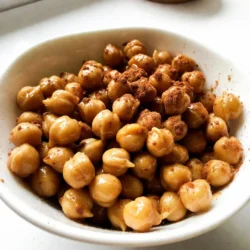 - 1 Dose (425 g) Kichererbsen, abgetropft und abgespült - 2 Esslöffel Olivenöl - 2 Esslöffel reiner Ahornsirup Kichererbsen sind die Basis dieses Snacks. Sie sind gesund, knusprig und voller Ballaststoffe. Olivenöl sorgt für den perfekten Geschmack und hilft, die Kichererbsen schön zu rösten. Der Ahornsirup bringt eine süße Note hinein, die mit dem Zimt harmoniert. - 1 Teelöffel gemahlener Zimt - ½ Teelöffel Vanilleextrakt - ¼ Teelöffel gemahlene Muskatnuss (optional) Zimt gibt den Kichererbsen einen warmen und würzigen Geschmack. Der Vanilleextrakt fügt eine feine Süße hinzu. Muskatnuss ist optional, aber sie kann dem Snack eine aufregende Tiefe verleihen. - ¼ Teelöffel Meersalz Ein wenig Meersalz hebt alle Aromen hervor. Es sorgt für einen perfekten Kontrast zur Süße des Sirups und dem Zimt. {{ingredient_image_2}} Heize deinen Ofen auf 200°C vor. Das sorgt für eine gleichmäßige Hitze. Lege ein Backblech mit Backpapier aus. Das Backpapier hilft, die Kichererbsen knusprig zu halten. Außerdem bleibt das Blech sauber. Nimm eine große Schüssel. Gib die abgetropften Kichererbsen hinein. Füge Olivenöl, Ahornsirup, gemahlenen Zimt, Vanilleextrakt, Meersalz und die Muskatnuss dazu. Rühre alles gut um. So sind die Kichererbsen gleichmäßig beschichtet. Das macht sie schmackhaft und süß. Verteile die Kichererbsen gleichmäßig auf dem Backblech. Achte darauf, dass sie in einer einzigen Schicht liegen. Röste sie im Ofen für 25-30 Minuten. Überwache sie während des Röstens. Rühre sie einmal um, damit sie goldbraun werden. So werden sie schön knusprig. Nach dem Rösten lasse sie kurz abkühlen. Sie bleiben auch beim Abkühlen knusprig. Um die besten Kichererbsen zu rösten, achten Sie darauf, dass sie gleichmäßig geröstet werden. Dies erreichen Sie, indem Sie die Kichererbsen in einer einzigen Schicht auf das Backblech legen. Wenn sie übereinander liegen, wird die Hitze nicht gleichmäßig verteilt. Frische Zutaten sind der Schlüssel zu einem großartigen Geschmack. Verwenden Sie frische Kichererbsen aus der Dose oder kochen Sie sie selbst. Achten Sie darauf, dass die Kichererbsen gut abgetropft sind. Feuchtigkeit kann die Knusprigkeit beeinträchtigen. Präsentieren Sie die Kichererbsen in einer kleinen Schüssel. Das macht sie zu einem tollen Snack. Sie können sie auch als knackigen Belag auf Salaten verwenden. Ein zusätzlicher Spritzer Zimt auf den Kichererbsen sorgt für mehr Aroma. Kombinieren Sie die Kichererbsen mit anderen Gerichten. Sie passen gut zu Quinoa oder Gemüsegerichten. Sie können sie sogar in Wraps oder Sandwiches einfüllen. Experimentieren Sie mit verschiedenen Gewürzen. Fügen Sie etwas Cayennepfeffer für einen scharfen Kick hinzu. Oder probieren Sie verschiedene Süßungsmittel. Honig oder Agavendicksaft sind tolle Alternativen zum Ahornsirup. Sie können auch mit verschiedenen Gewürzen spielen. Zum Beispiel können Sie Kreuzkümmel oder Paprika verwenden, um den Geschmack zu variieren. Pro Tipps Richtige Kichererbsenwahl: Verwenden Sie am besten frische, getrocknete Kichererbsen, die Sie vorher einweichen und kochen. Diese sind oft geschmackvoller und haben eine bessere Textur als Dosenkichererbsen. Variieren Sie die Gewürze: Experimentieren Sie mit verschiedenen Gewürzen wie Paprika oder Kreuzkümmel, um den Geschmack der Röstkichererbsen nach Ihrem persönlichen Geschmack anzupassen. Knusprigkeit maximieren: Stellen Sie sicher, dass die Kichererbsen gut abgetropft sind, bevor Sie sie rösten. Nasses Gemüse kann das Rösten behindern und zu einer weniger knusprigen Textur führen. Aufbewahrungstipps: Lagern Sie die gerösteten Kichererbsen in einem luftdichten Behälter, damit sie knusprig bleiben. So sind sie auch am nächsten Tag noch ein toller Snack! {{image_4}} Sie können Ihr Rezept süßer machen. Fügen Sie einfach Honig oder Agavendicksaft hinzu. Diese süßen Zutaten geben den Kichererbsen mehr Geschmack. Honig hat eine schöne, goldene Farbe. Agavendicksaft ist eine gute, vegane Option. Beide machen die Kichererbsen klebrig und lecker. Mischen Sie sie einfach mit den Kichererbsen, bevor Sie sie rösten. Für eine herzhafte Note können Sie Kräuter und Gewürze nutzen. Oregano oder Thymian passen gut zu Kichererbsen. Diese Kräuter geben dem Snack eine andere Richtung. Mischen Sie die Kräuter mit den Kichererbsen und den anderen Zutaten. Dies macht Ihr Gericht spannend und aromatisch. Probieren Sie auch Paprika oder Knoblauchpulver für mehr Geschmack. Möchten Sie es scharf? Fügen Sie Cayennepfeffer oder Paprika hinzu. Diese Gewürze bringen einen tollen Kick. Sie können die Menge nach Ihrem Geschmack anpassen. Ein bisschen macht den Unterschied. Rühren Sie die scharfen Gewürze gut in die Mischung. So wird jede Kichererbse gleichmäßig gewürzt. Um Ihre gerösteten Kichererbsen frisch zu halten, wählen Sie einen luftdichten Behälter. Glasbehälter oder Kunststoffbehälter mit einem festen Deckel sind ideal. Stellen Sie sicher, dass die Kichererbsen vollständig abgekühlt sind, bevor Sie sie einlagern. So vermeiden Sie Feuchtigkeit, die die Knusprigkeit beeinträchtigen kann. Geröstete Kichererbsen bleiben bei richtiger Lagerung etwa eine Woche frisch. Lagern Sie sie an einem kühlen, trockenen Ort. Vermeiden Sie direkte Sonneneinstrahlung oder Wärmequellen. Wenn Sie die Kichererbsen länger aufbewahren möchten, können Sie sie auch im Kühlschrank lagern. Sie werden aber etwas weniger knusprig sein. Um die Knusprigkeit der Kichererbsen wiederherzustellen, heizen Sie Ihren Ofen auf 180°C (350°F) vor. Legen Sie die Kichererbsen auf ein Backblech und rösten Sie sie für 5 bis 10 Minuten. Achten Sie darauf, sie regelmäßig umzurühren, damit sie gleichmäßig warm und knusprig werden. So können Sie den köstlichen Snack immer wieder genießen! Geröstete Kichererbsen bleiben etwa eine Woche frisch. Lagern Sie sie in einem luftdichten Behälter. Die Kichererbsen sollten an einem kühlen, trockenen Ort stehen. Vermeiden Sie Feuchtigkeit, denn sie macht die Kichererbsen weich. Für beste Ergebnisse essen Sie sie innerhalb von drei bis fünf Tagen. So bleiben sie knusprig und lecker. Ja, Kichererbsen können ohne Öl geröstet werden. Sie werden jedoch weniger knusprig. Um dies zu tun, spülen Sie die Kichererbsen ab und trocknen Sie sie gut. Dann können Sie die Gewürze direkt hinzufügen. Legen Sie die Kichererbsen auf das Backblech. Rösten Sie sie wie gewohnt, aber achten Sie darauf, dass sie nicht verbrennen. Kichererbsen sind sehr nahrhaft. Sie enthalten viel Protein, Ballaststoffe und Vitamine. Eine Portion Kichererbsen liefert Eisen, Magnesium und Folsäure. Diese Nährstoffe unterstützen die Gesundheit. Kichererbsen helfen, den Blutzuckerspiegel zu regulieren. Sie fördern auch die Verdauung und halten lange satt. Kichererbsen sind vielseitig und einfach zu rösten. In diesem Artikel haben wir alle Zutaten und Schritte besprochen. Wir haben gelernt, wie man Kichererbsen mit Gewürzen verfeinert und sie perfekt röstet. Außerdem haben wir Tipps zur Lagerung und Haltbarkeit gegeben. Teste verschiedene Rezepte und Variationen aus. Kichererbsen sind gesund und lecker. Du kannst sie süß, herzhaft oder scharf genießen. Probiere es aus und finde deinen Favoriten!